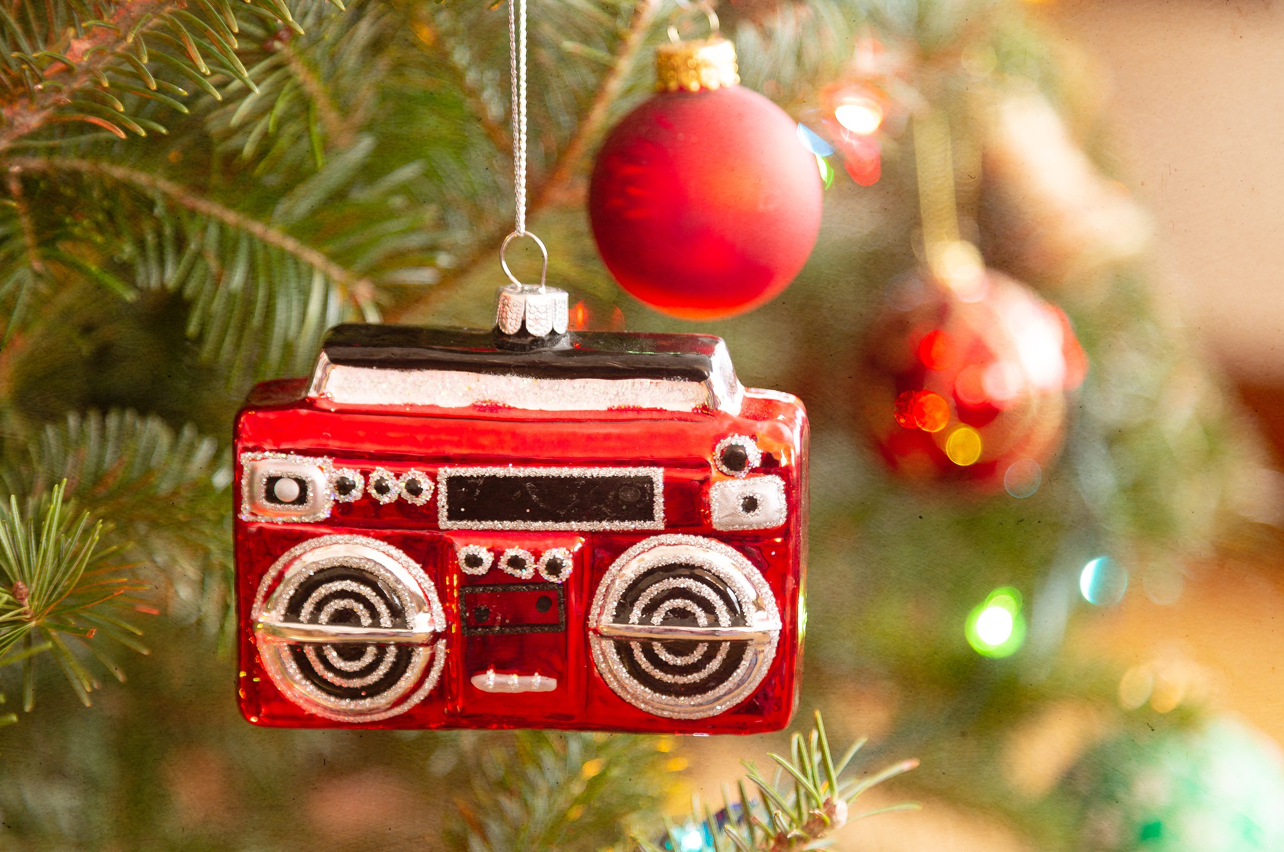 A christmas ornament in the shape of a radio or boom box hanging on the Christmas tree.
