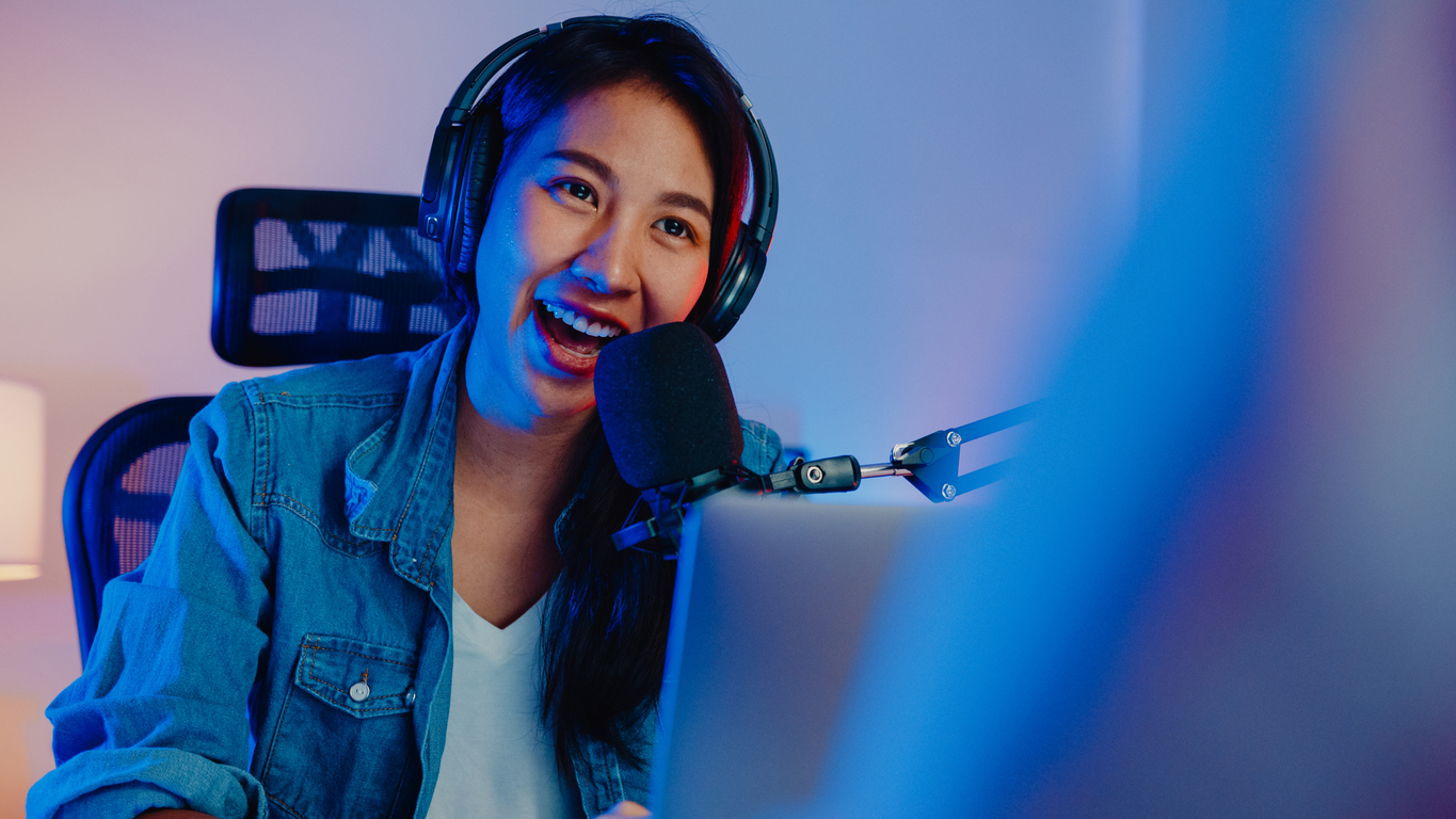 Young woman sitting in front of a podcast microphone.
