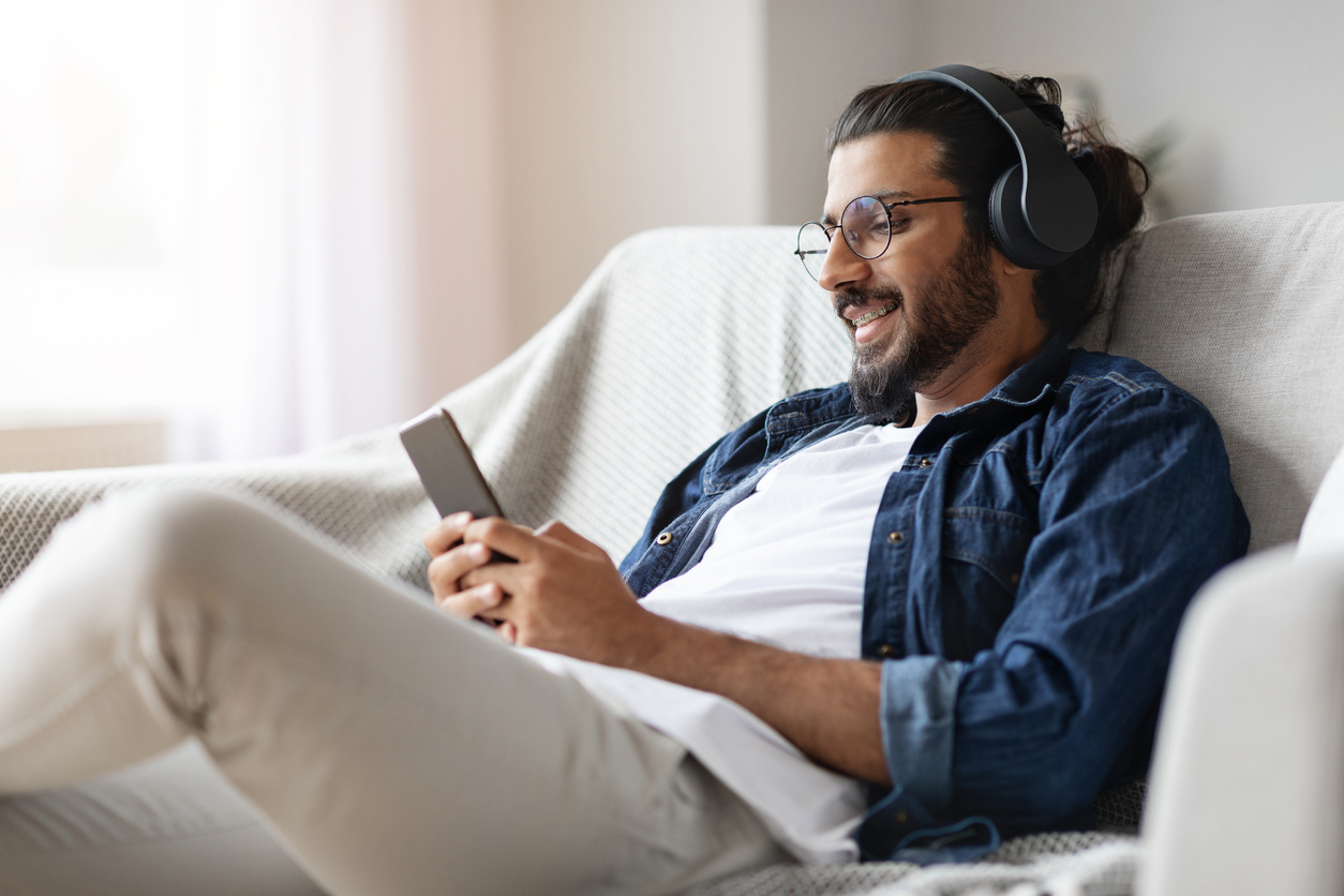 Man sitting on the couch wearing headphones.