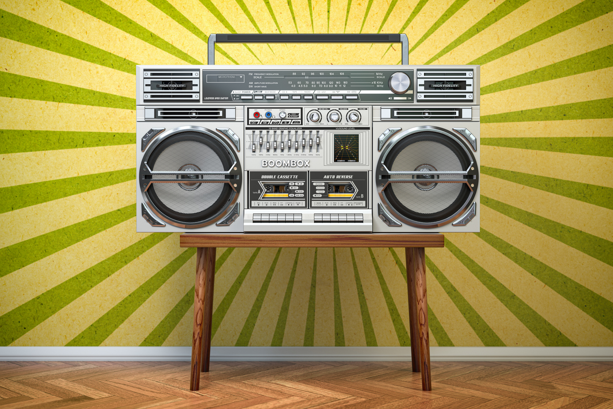Grey boombox on a table with a yellow background.