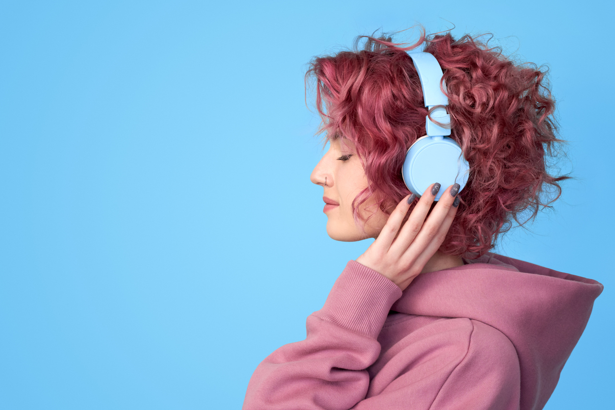 Red headed woman listening to music with blue headphones on.
